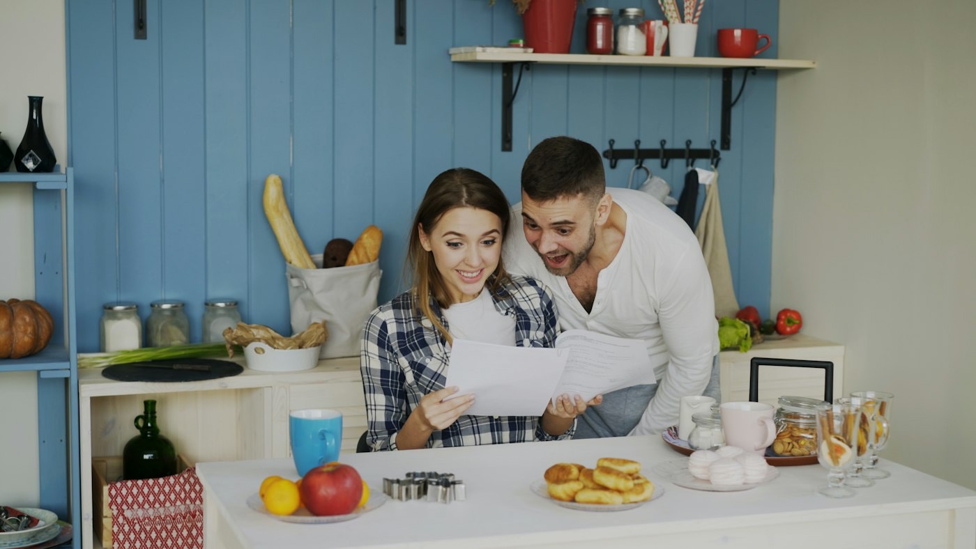 A couple reading through papers together at a kitchen table