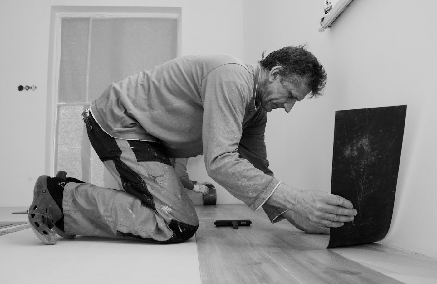 A floor installer on his knees setting a large tile into place