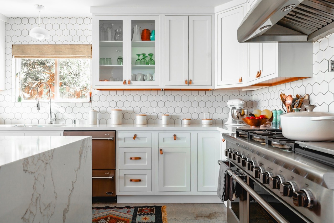 A white kitchen with glass-front cabinets, a range cooker and hexagon tile